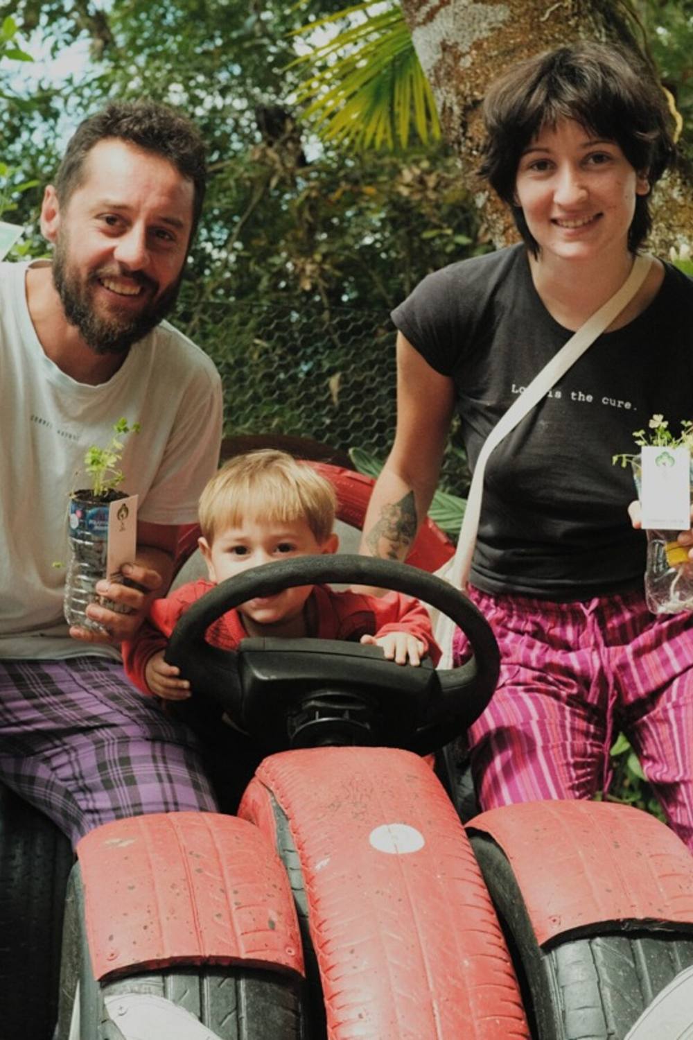 Família mostrando as mudas plantadas em vasos de garrafa PET