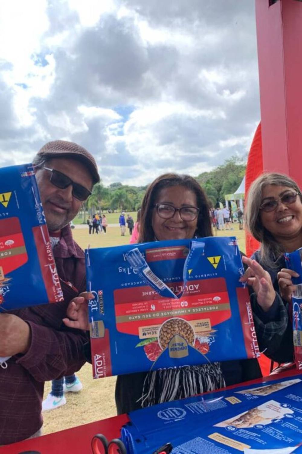 Três participantes sorrindo com suas ecobags feitas de saco de ração