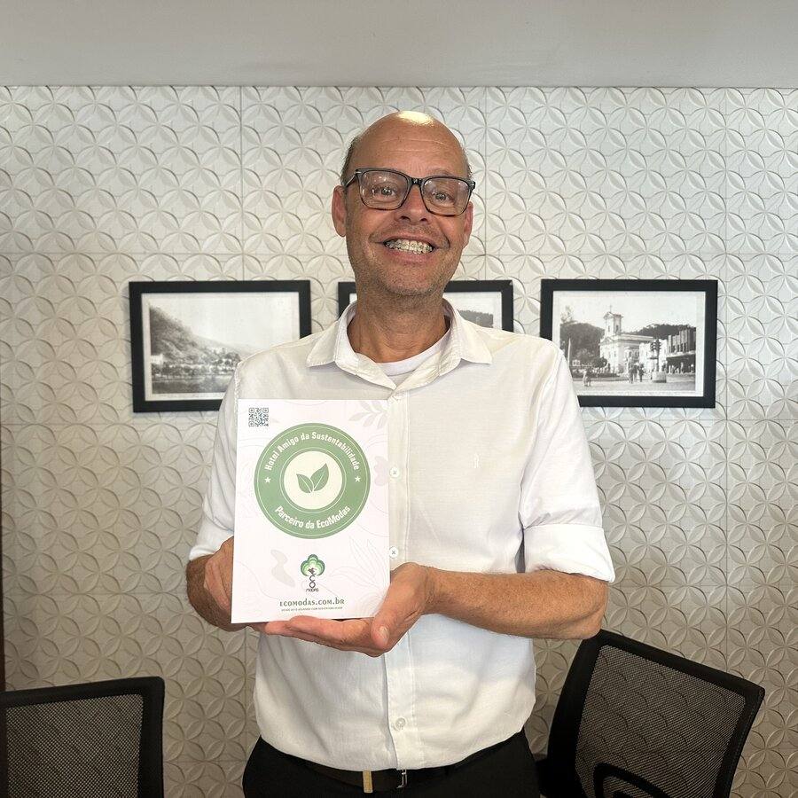 Gestor de hotel parceiro segurando o certificado do Selo Verde Hotelaria