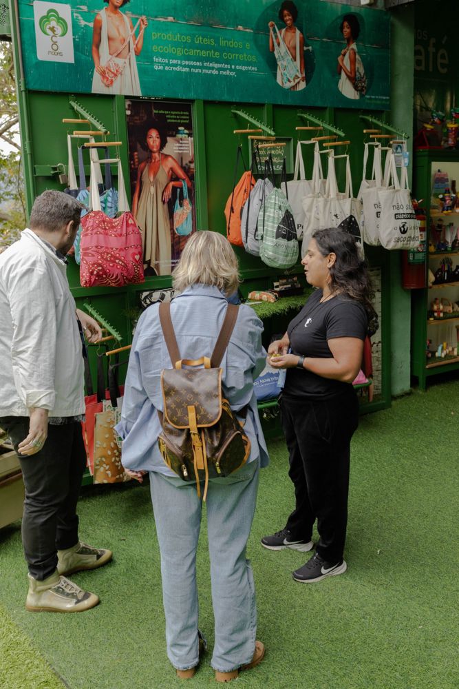 Visitantes na parede de ecobags e produtos da loja