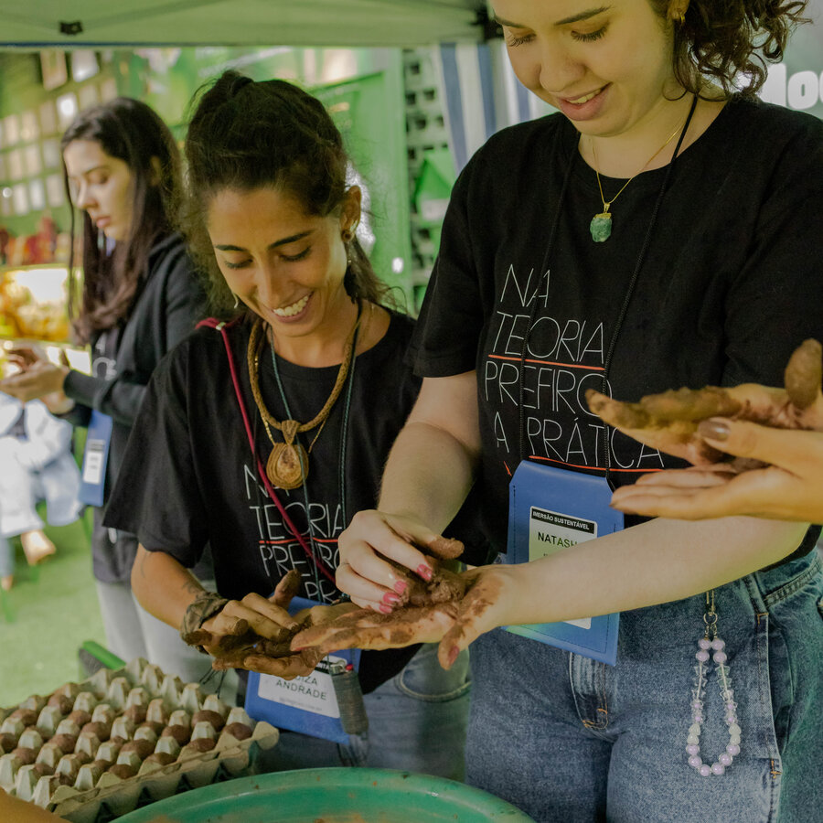 Grupo de participantes moldando bombas de sementes com as mãos, com bandejas de ovo ao fundo