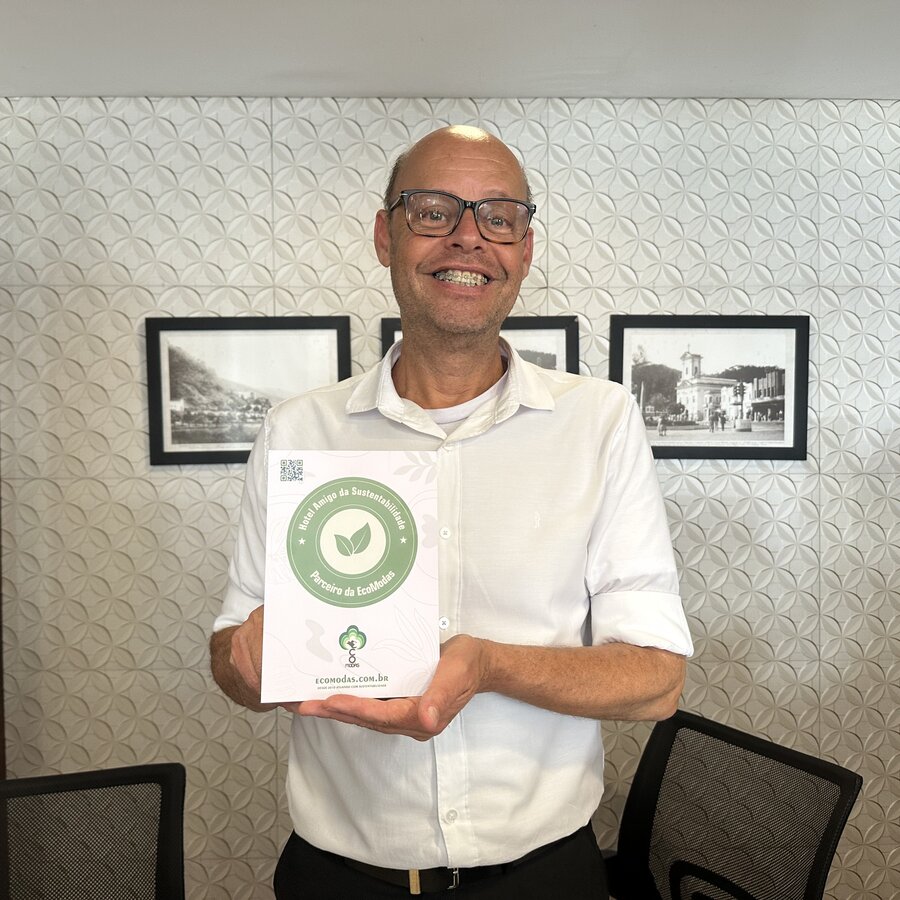 Gestor de hotel parceiro segurando o certificado do Selo Verde Hotelaria